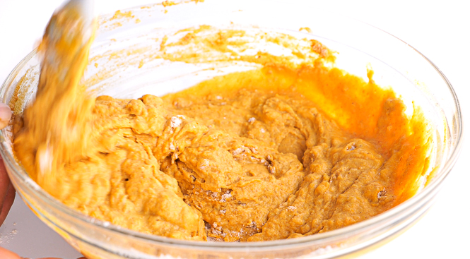 stirring pumpkin pancake batter in clear bowl